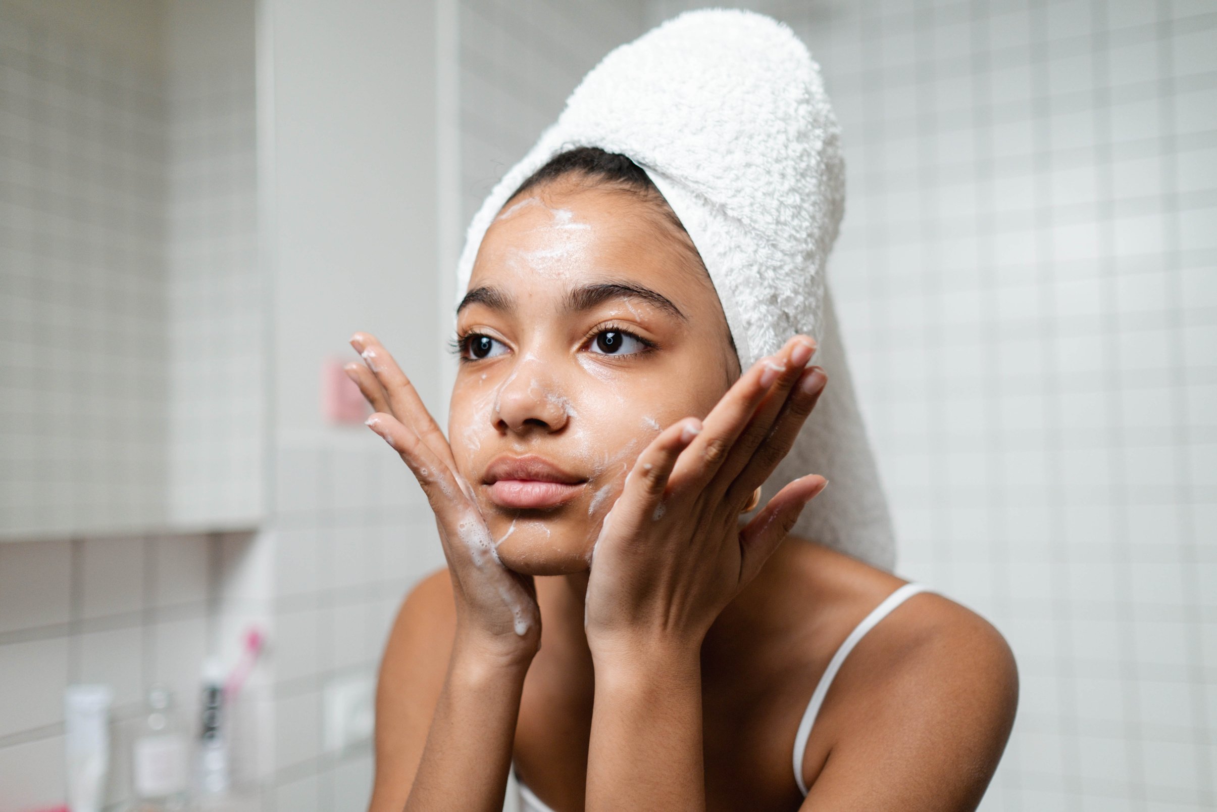 Woman in White Tank Top Washing Her Face With Soap